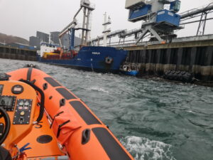 Kyle RNLI lifeboat approaches the stricken scallop boat. Photograph: Kyle RNLI. NO-F51-Vessel-between-cargo-boat-pier-small-